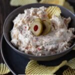 Green olive dip with chips and sliced olives.