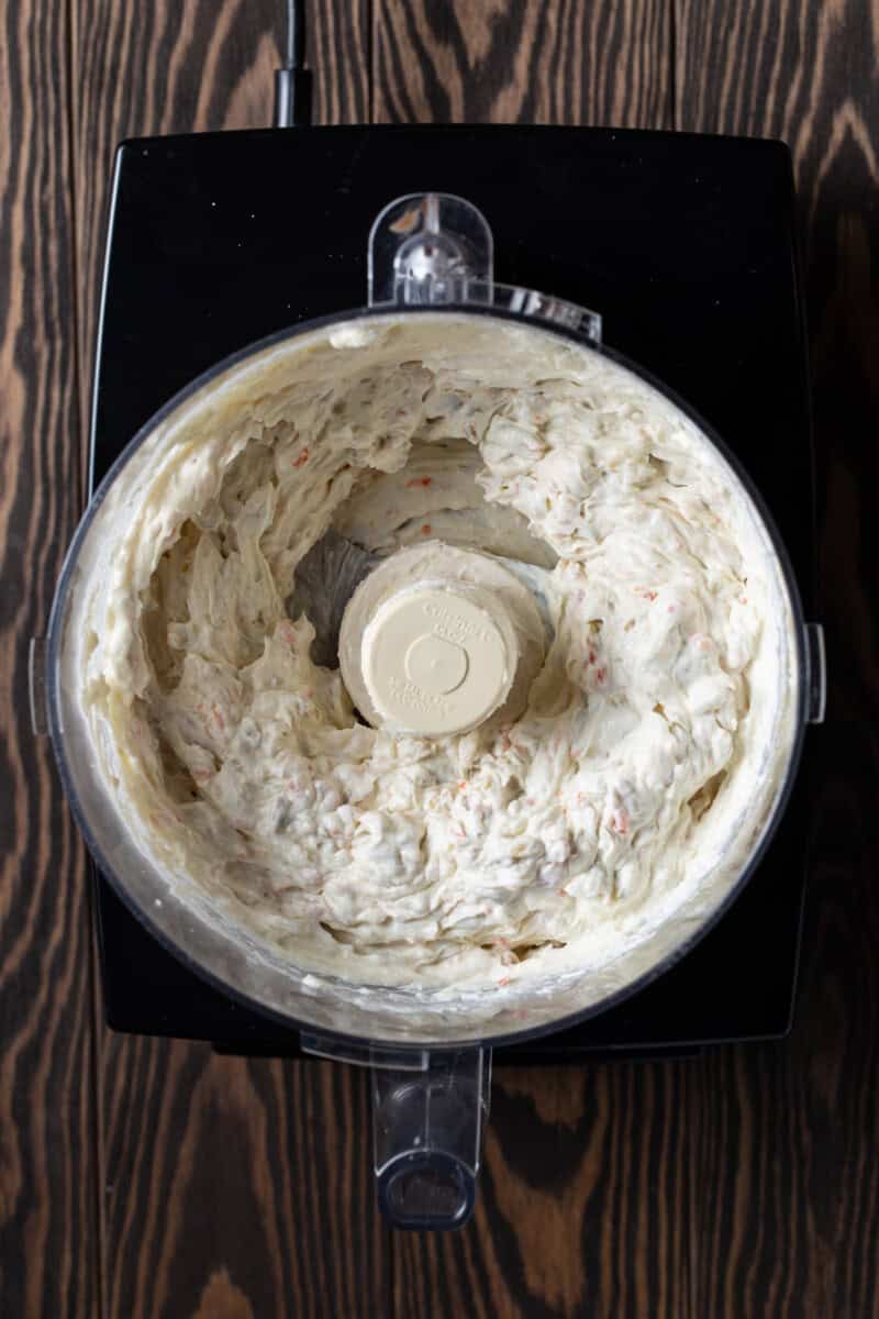 Blended Green olive dip in bowl of food processor.