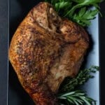 Cooked turkey breast on black plate.