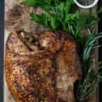 Herbs and cooked turkey on cutting board.