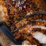 Sliced Herb Roasted Bone-In Turkey Breast on board with knife.