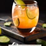 Aprol Gin drink in low ball glass filled with ice and cucumber slices.