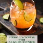 Single glass of aperol gin drink with ice and lime wedge.