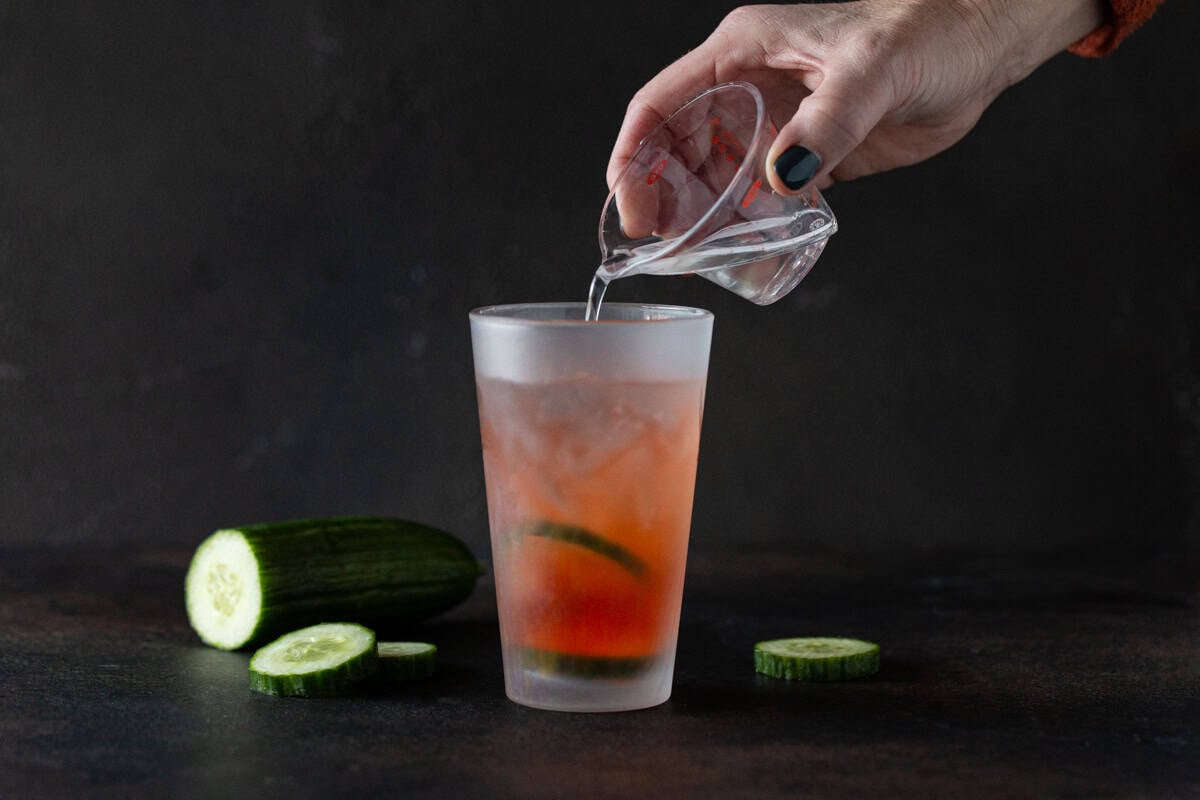 simple syrup being poured into full shaker.