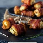Toothpick in Bacon Cream Cheese Bite on a black plate.