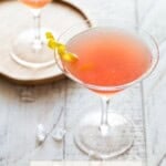 Two martini glasses filled with cosmos and garnished with lemon twists.
