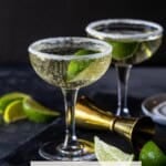 two glasses filled with gin prosecco cocktails and garnished with lime wedge.