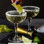 lime wedge being placed into sugar rimmed coupe glass.