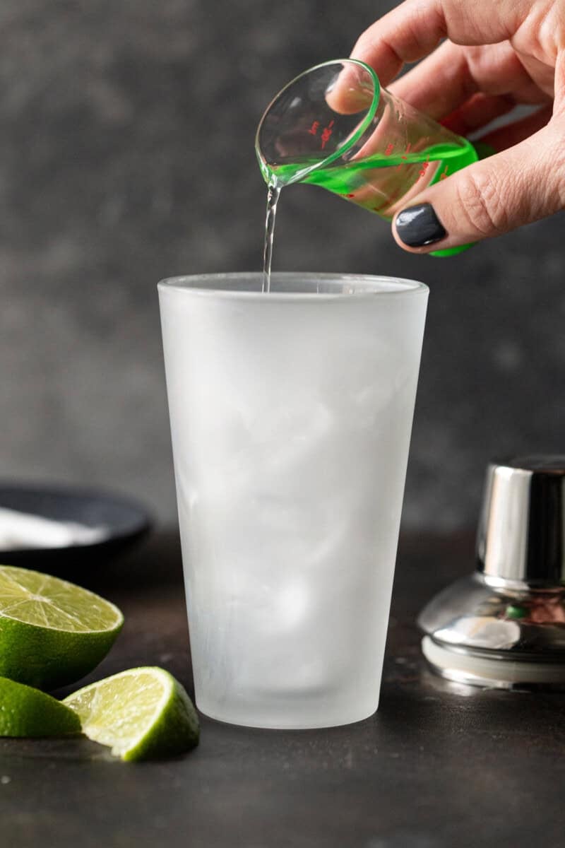 Gin being poured into shaker filled with ice.