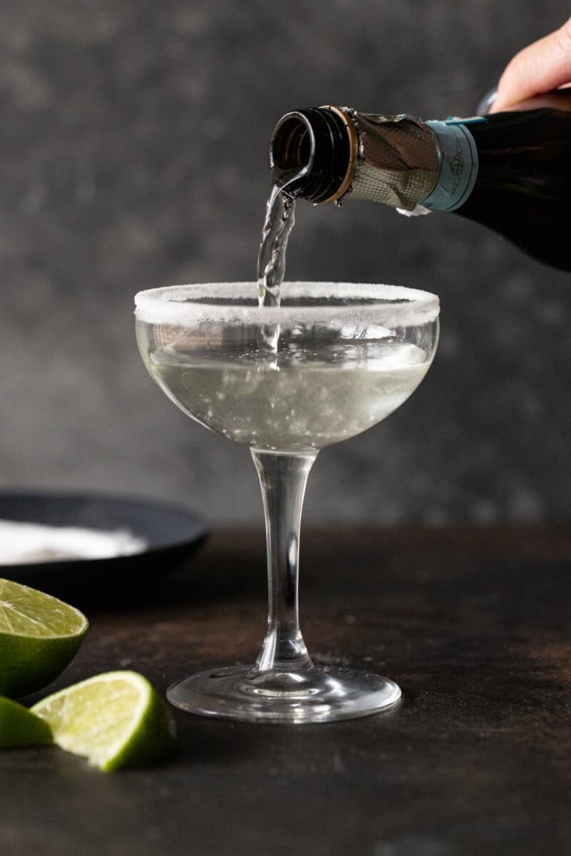 Prosecco being poured into a sugar rimmed coupe glass.