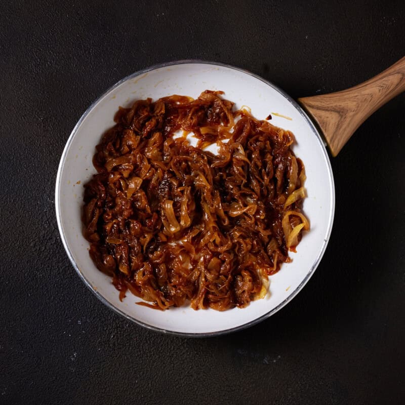 Caramelized onions in a white skillet.