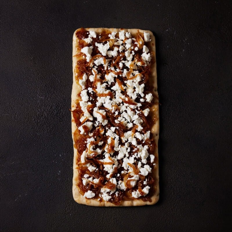 A flatbread spread with fig jam and topped with goat cheese and caramelized onions.