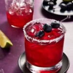 blueberry margarita with salted rim and plate of blueberries.
