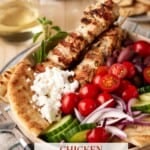 Chicken skewers with pita, tomatoes, olives, cucumber and red onion.