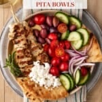 Bowl filled with Chicken Souvlaki, pita, cucumbers, feta cheese and olives.
