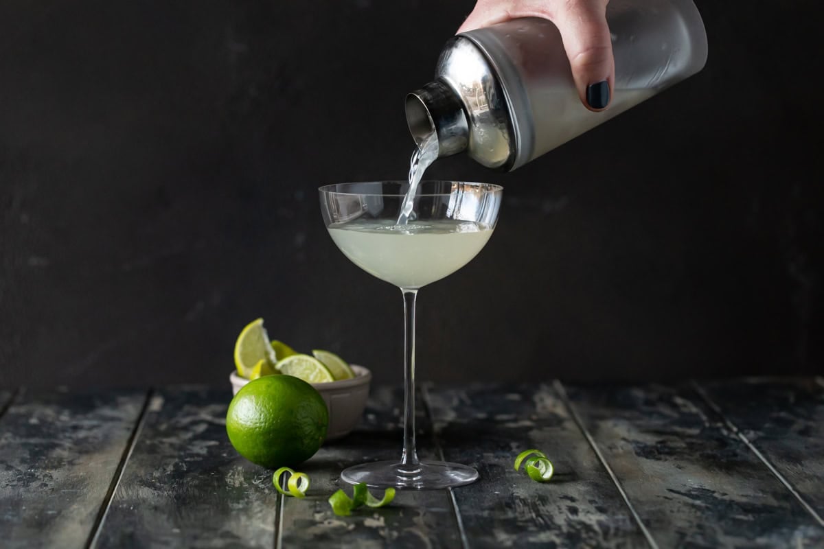 Shaker pouring martini into glass.