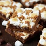 Two baked s'mores bars stacked on each other and surrounded by other cut bars.