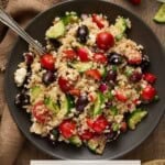 Quinoa salad on a brown plate with a brown linen napkin and red peppers.