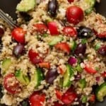 Mediterranean Quinoa Salad on a gray plate with a sliver fork.
