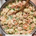 Deep Saute Pan filled with One-Pot Creamy Shrimp Pasta with Peas and a peach napkin.