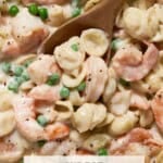 Pasta, peas and Shrimp in a creamy sauce with a spoon.