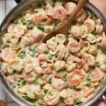 Deep Saute pan filled with creamy shrimp pasta and a spoon for serving.