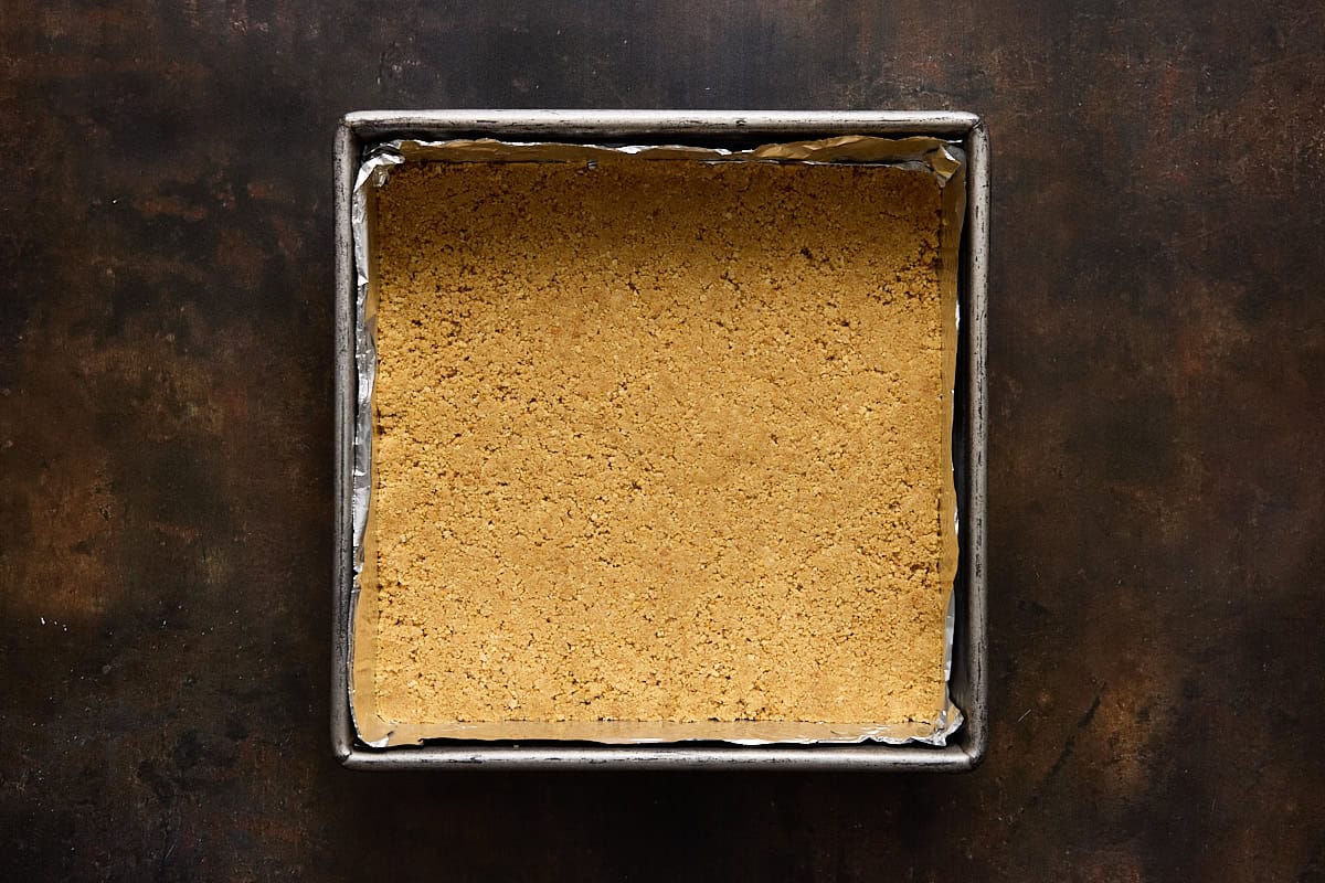 Graham cracker crust pressed into the bottom of a foil lined square metal baking pan.