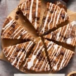 A whole Sour Cream Chocolate Chip Coffee Cake cut into slices with drizzle on top and a cup of coffee.