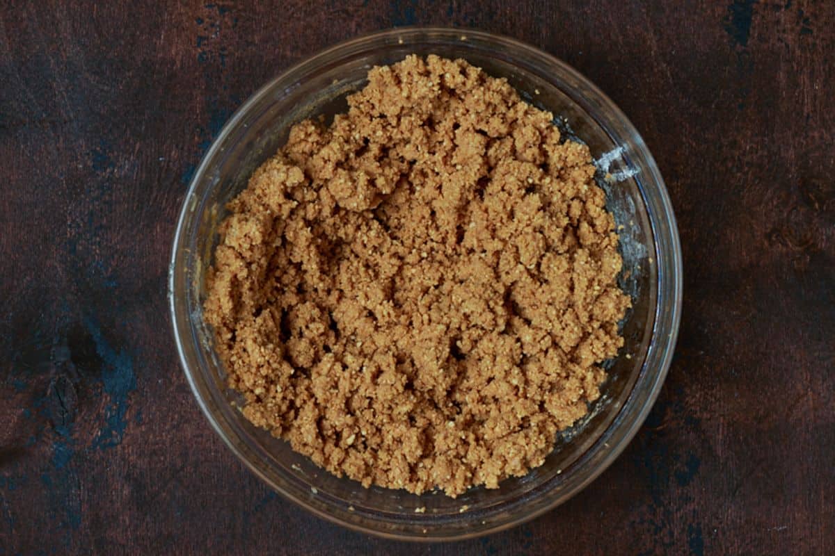 A glass bowl filled with graham cracker crust for baked s'mores bars.