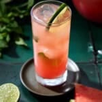 A single watermelon mojito in a highball glass. Garnished with mint and a lime wheel.