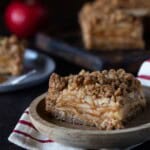 A slice of apple crisp bars on a wooden plate.