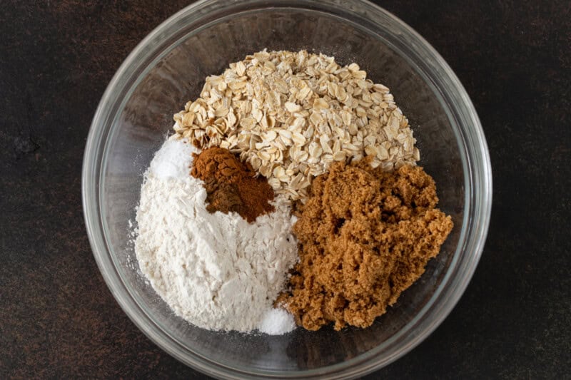 Oats, brown sugar, flour and fall spices in a glass bowl.
