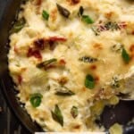 Bubbly baked asiago artichoke dip with triscuits for eating.