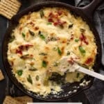 Baked artichoke dip with sun dried tomatoes and green onion in cast iron.