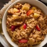 Bake steel cut oatmeal in a bowl with apple chunks and syrup.