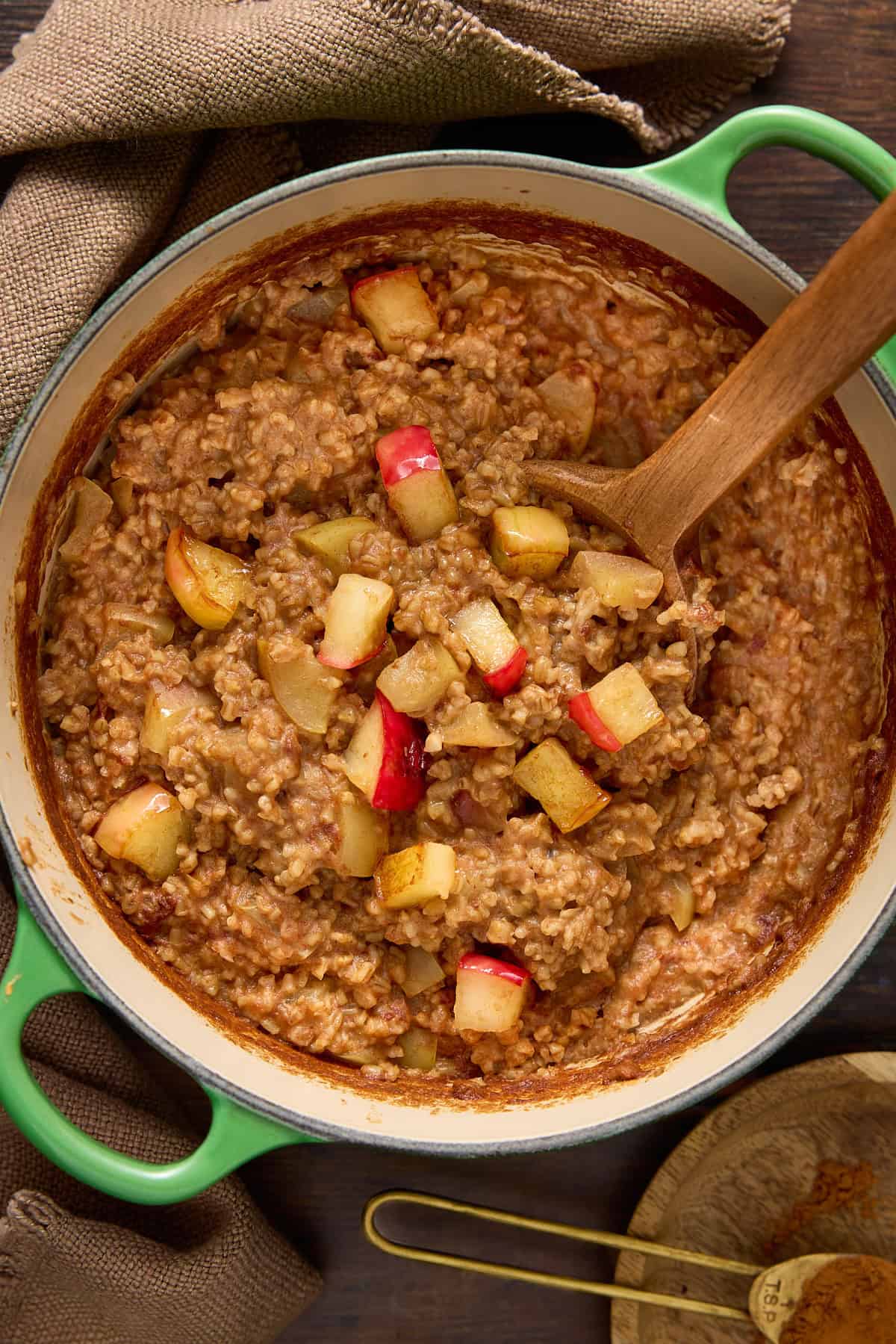 Baked steel cut oats with apple chunks and a spoon for stirring.