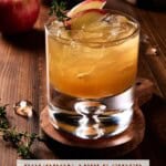 Lowball glass filled with bourbon apple cider cocktail and garnished with thyme and apple slices.