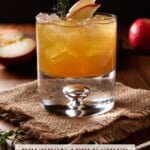 Lowball glass filled with bourbon apple cider cocktail on a burlap napkin.