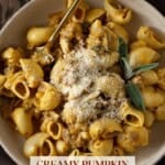 A beige bowl with pumpkin sausage pasta and topped with parmesan cheese.