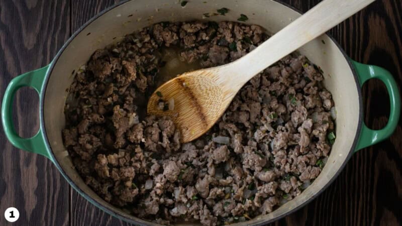 Italian sausage, onions and garlic browned in a green dutch oven.