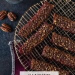 Slices of cooked candied bacon on rack with pecans and cayenne.