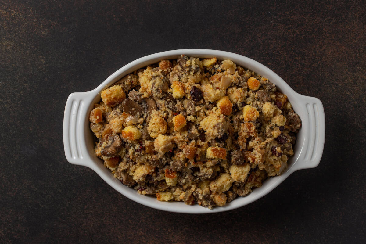 Unbaked cornbread stuffing in a white oval casserole dish.