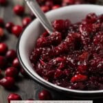 Chunky homemade cranberry sauce in a white bowl with a silver spoon.