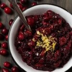 A white bowl filled with chunky homemade cranberry sauce and topped with lemon zest.