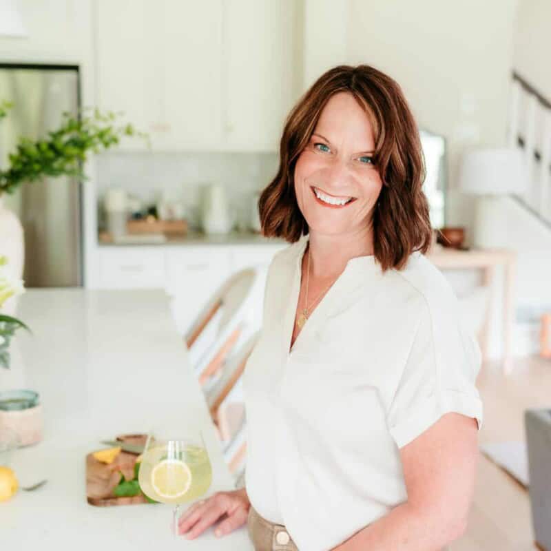 woman standing by counter smiling with a wine glass.