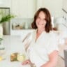 woman standing by counter smiling with a wine glass.