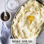 Mashed potatoes topped with melted butter and black pepper in an oval stainless steel baking dish, with whole potatoes, salt, and pepper alongside and the text "Make-Ahead Mashed Potatoes."