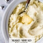 Mashed potatoes with a pat of butter and a serving spoon in a white slow cooker, with the text "Make-Ahead Mashed Potatoes."